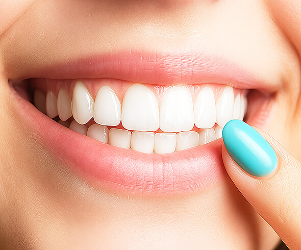 Nahaufnahme eines strahlenden Lächelns mit weißen Zähnen, Finger mit türkisfarbenem Nagellack zeigt darauf.