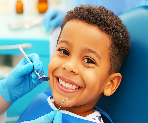 Lachender Junge auf dem Zahnarztstuhl mit geöffnetem Mund, Zahnarzt hält zahnärztliche Instrumente.