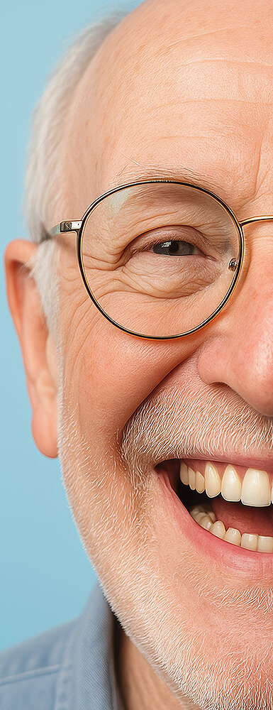 Nahaufnahme der linken Gesichtshälfte einer lächelnden Frau mit Brille; ihre Zähne sind sichtbar und wirken gepflegt.