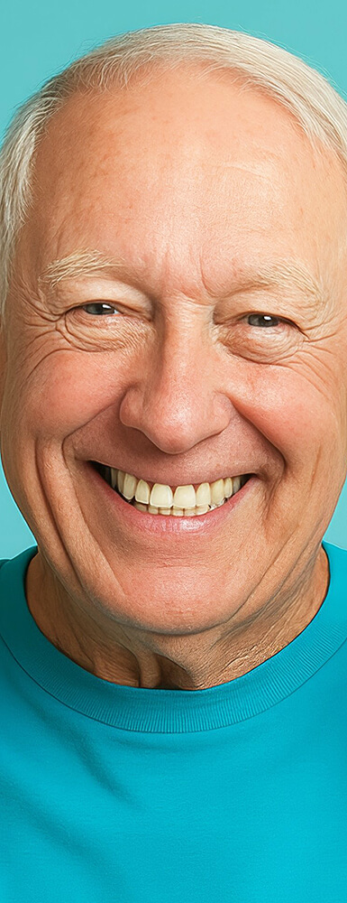 Älterer Mann mit grauen Haaren und freundlichem Lächeln vor hellblauem Hintergrund.