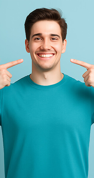 Junger Mann zeigt mit beiden Händen auf sein Lächeln.