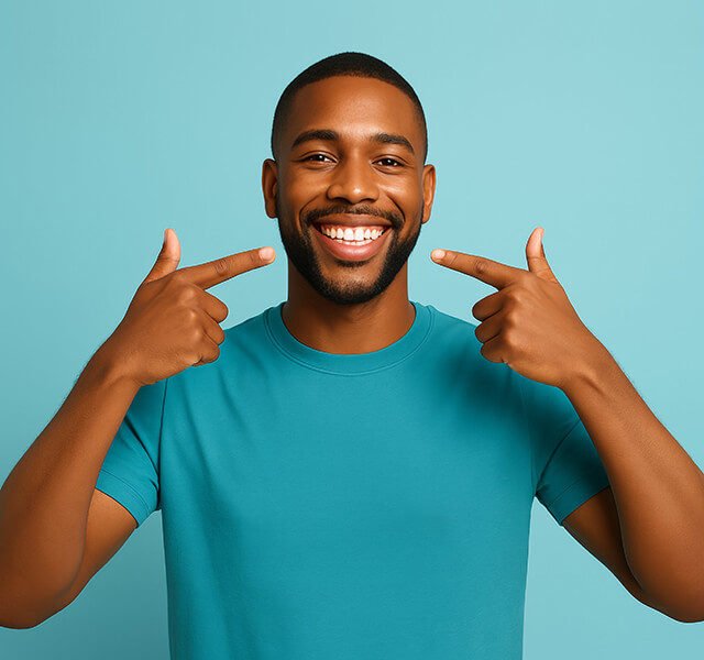 xxxxxxLächelnde Person zeigt mit beiden Händen auf ihre Zähne, türkisfarbener Hintergrund.xxxxxxx